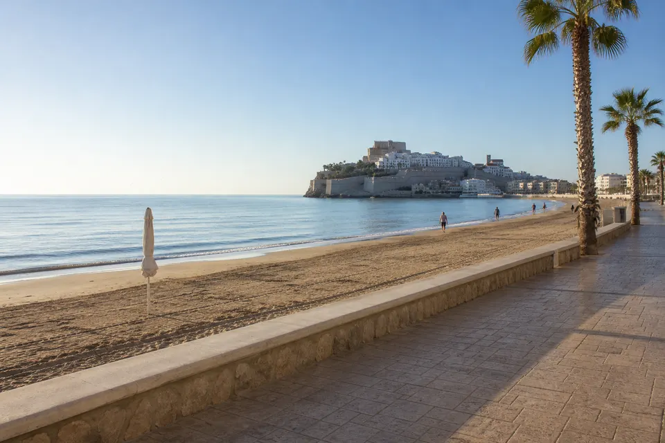 Recreación generada con IA de una mañana despejada y mar tranquilo en una playa inspirada en Peñíscola