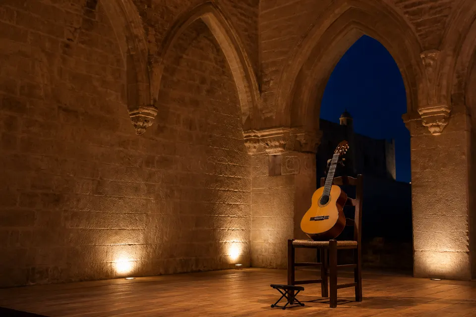 Guitarra clásica preparada en un salón histórico de piedra