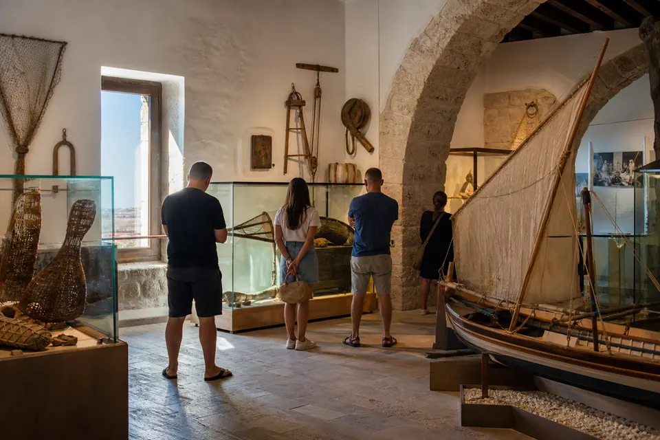 Recreación generada con IA del interior de un museo marítimo con visitantes y artes de pesca